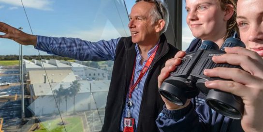 Photo of three people looking out the window onto Parafield runway