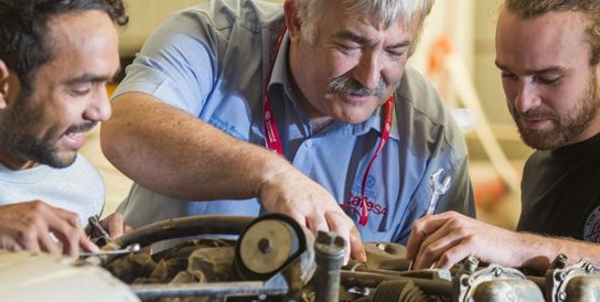 Image of three men repairing an engine